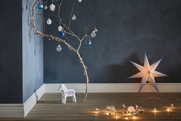 VINTERFEST Christmas tree decorations on a branch with wooden horse and STRÅLA lighting nearby.