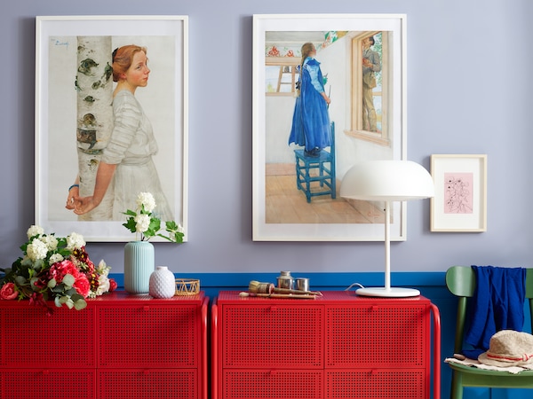 Wall with picture frames and some storage in red with a lamp, plants and a STILREN vase with a flower.